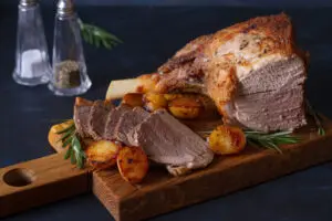 Roast leg of lamb with potatoes and rosemary on dark background